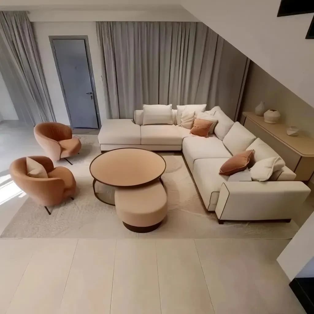 The sectional sofa remains a constant feature, but the pillows now incorporate soft peach, rust, and off-white tones